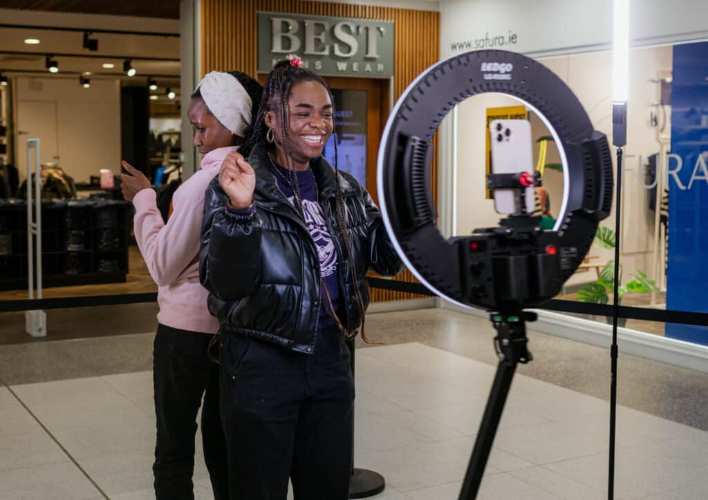 Two women smiling and posing on a platform taking a 360 video