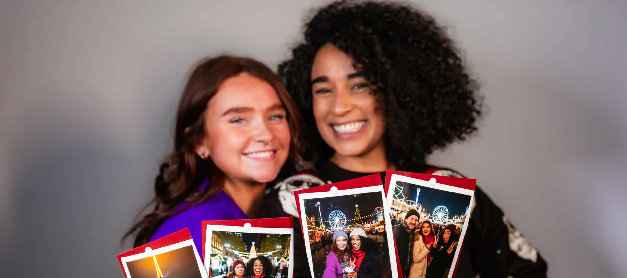 Two women holding printed photos 